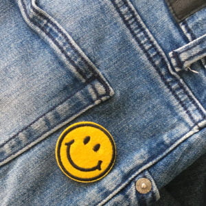 Tygmärke leende Emoji på blå jeans