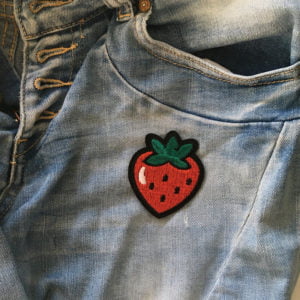 Röd jordgubbe med svarta frön påstrukna på jeans