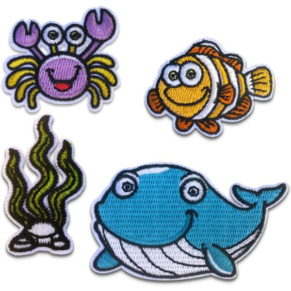 Fyra broderade tygmärken föreställande en val, en krabba, sjögräs och en fisk